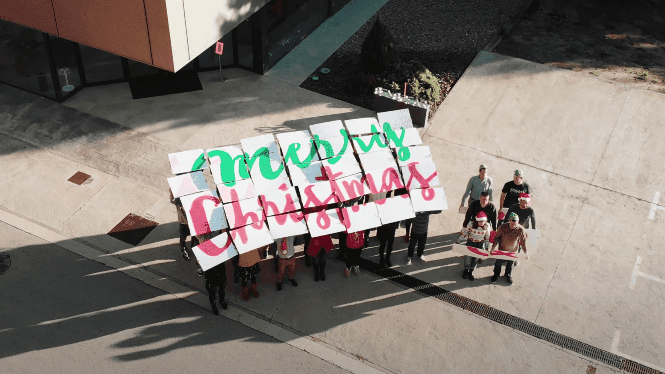 Employees holding up 'Merry Christmas' signs for a company video