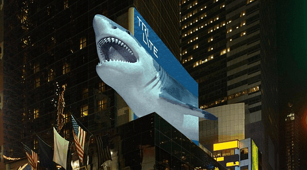 A billboard on top of a building, with a large 3D shark appearing to emerge from the billboard.