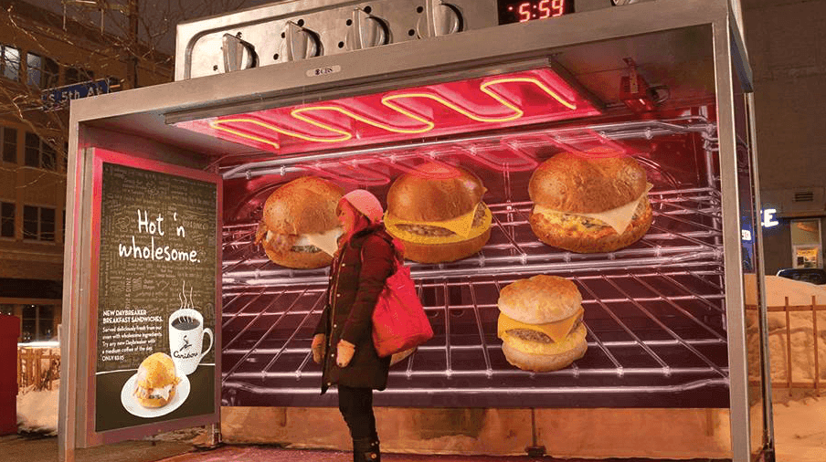 A heated bus stop that is designed to look like an oven with sandwiches inside.